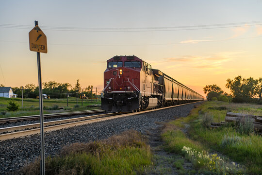Red freight train traveling through countryside at sunset