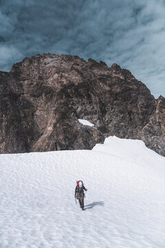 Mountaineer Ascending Snowy Slope Below Rocky Peak