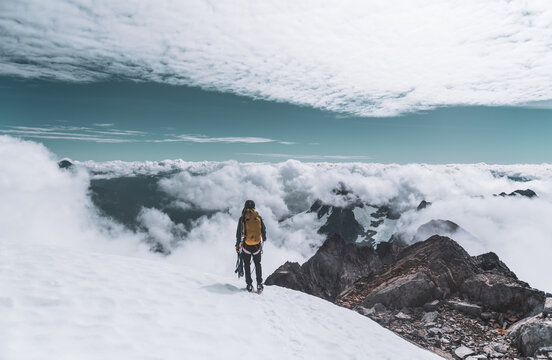 Climber Standing on Snowy Ridge Overlooking Cloud Inversion