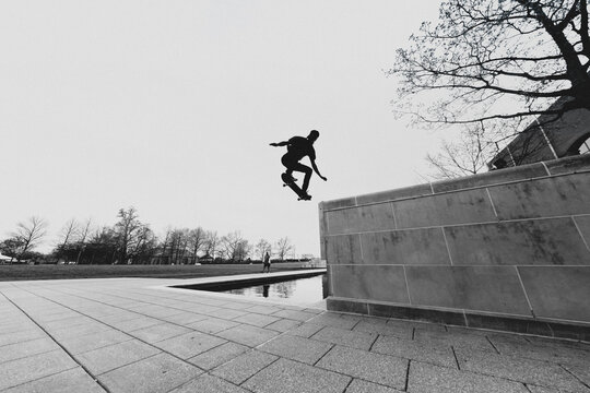 Skateboarder performs an aerial trick above a concrete wall.