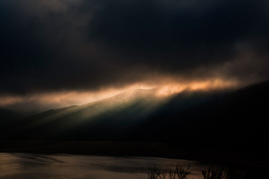 morning sunbeams breaking through clouds with dark smoke from