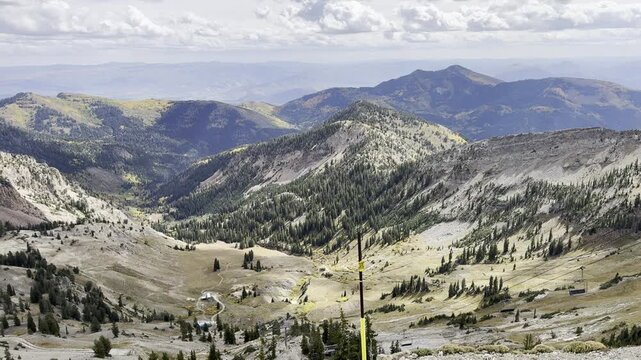 Point of view from an aerial tramway overlooking a vast rugged mountain range and deep valley.