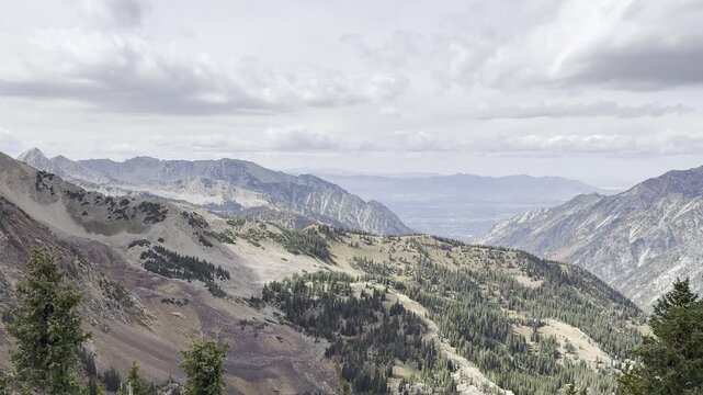 Point of view from an aerial tramway overlooking a vast rugged mountain range and deep valley.