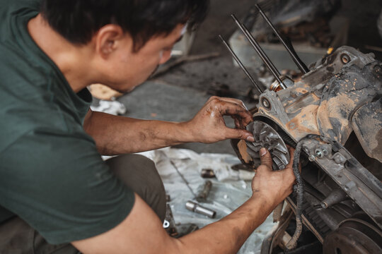 Mechanic installing a cooling fan on a motorcycle engine during repair in a workshop.