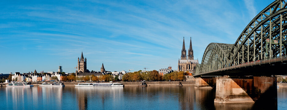 View of Cologne with a river and a bridge under a clear sky
