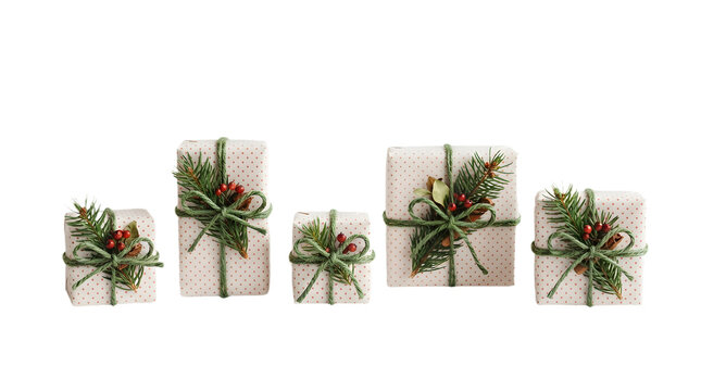A collection of five small gift boxes wrapped in white paper with red polka dots, decorated with pine sprigs and berries, isolated on transparent background