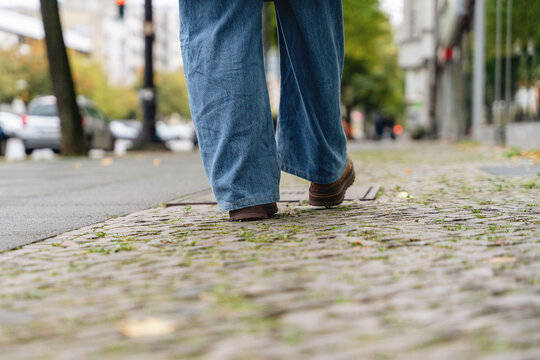 Woman walking along cobblestone street in an urban area on cloudy day
