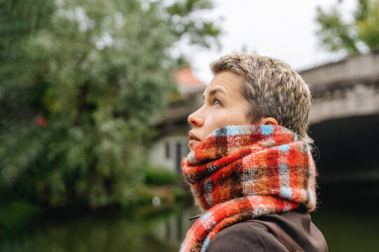 Person looks up near river with bridge in the background during  