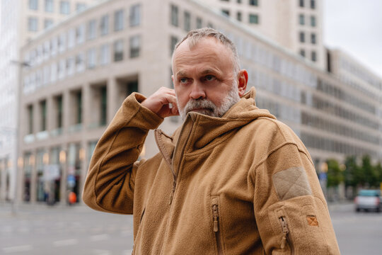 Man adjusts his clothing in an urban setting during daylight hours