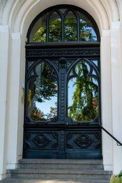 Entrance door with intricate design and reflection of trees