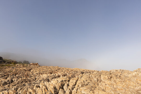fog bank and afternoon sunlight over rocky coastline of Hermanus, South Africa