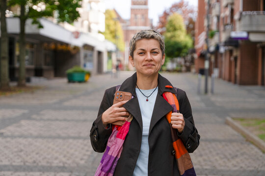 Woman walking in a city street with a smile, enjoying a day outdoors