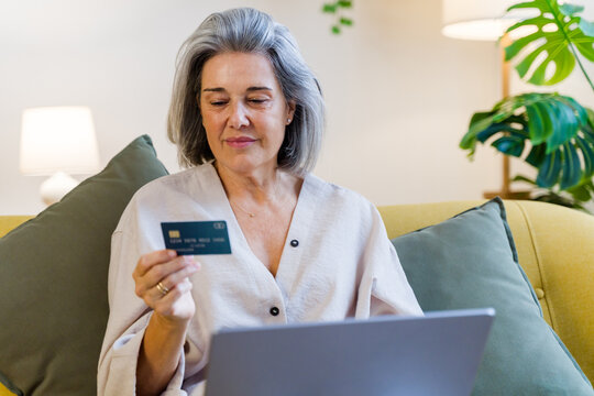 Middle-aged white woman using credit card and laptop at home