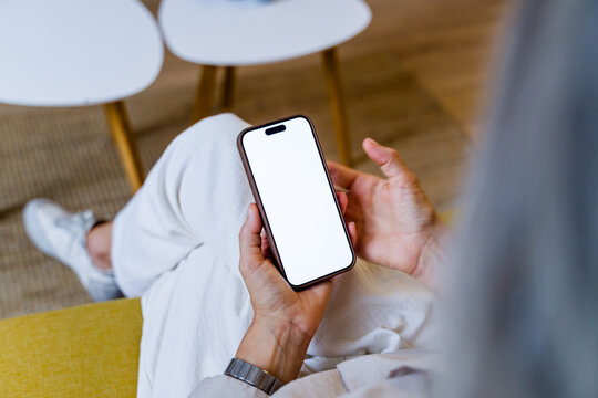 Person holding smartphone with blank white screen indoors