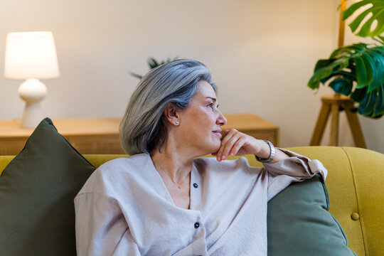 Mature white woman relaxing on sofa in cozy living room