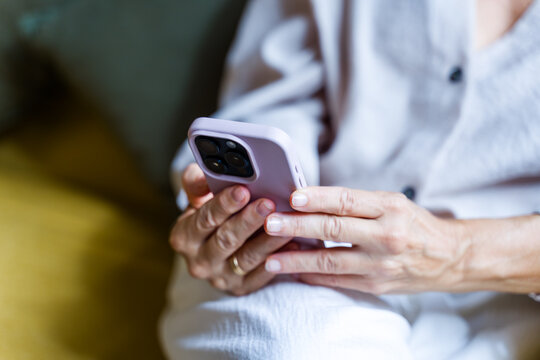 White adult hands holding and using a smartphone indoors