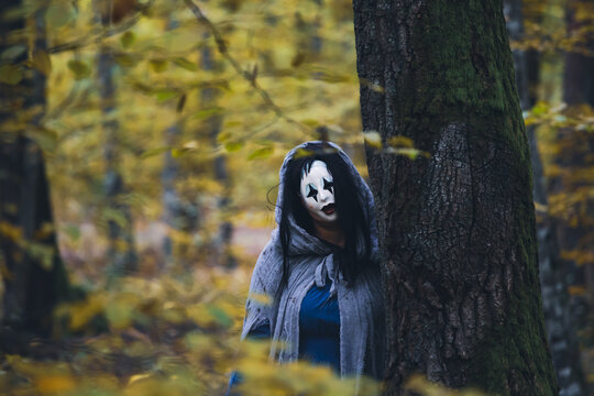 Horror background of a ghostly figure in enchanted a forest on a moody autumn day.