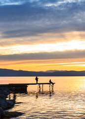 Fototapeta premium Two people on a pier at sunset on Lake Ohrid