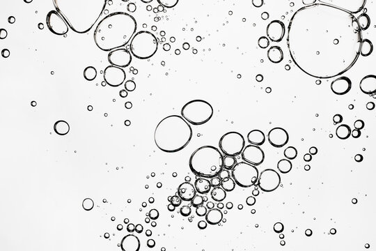 Transparent liquid bubbles creating an abstract pattern on white background