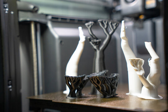 3D printed black and white tree support structures resting on a build plate inside a printer chamber.