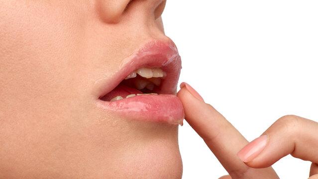 Young woman touching moist lower lip in closeup on transparent background. Lip balm retail, winter skincare, beauty education concept.