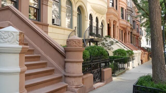 New York City townhouse buildings, brownstone row houses in Manhattan or Brooklyn, United States of America. Classic buildings on residential district street. Real estate property. Rowhouse townhome.