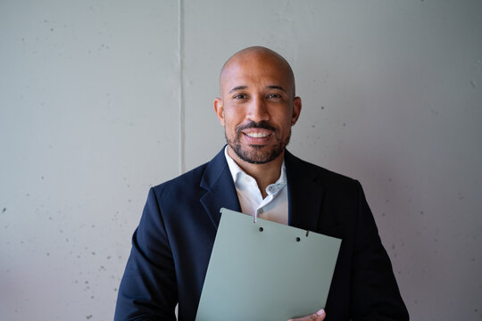 Smiling businessman in suit holding folder indoors