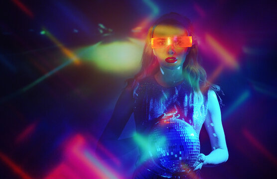 A woman holds a disco ball in futuristic neon light