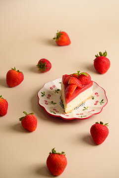 Slice of Strawberry Cheesecake on Ceramic Plate Surrounded by Fresh Strawberries