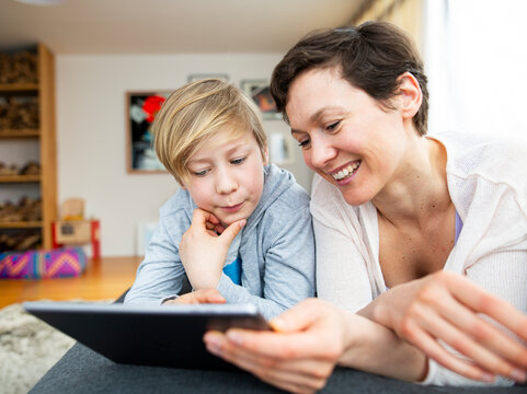 Mother and son are using a tablet in the living room