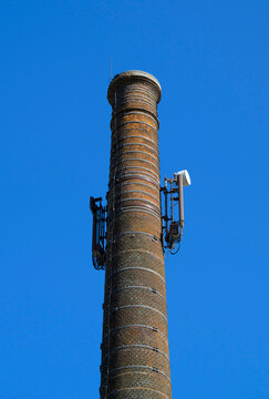 An old industrial brick chimney holds a mobile network antenna