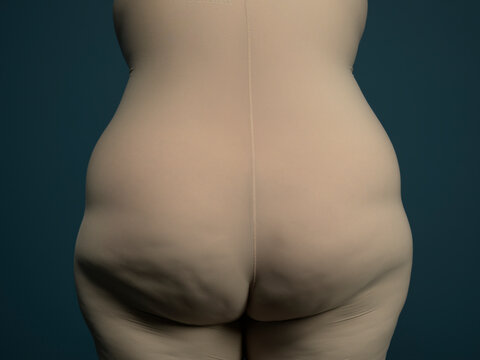 Woman shows her back and bottom covered in beige underwear