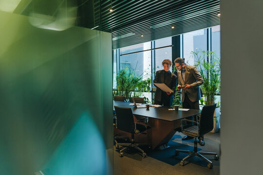 Businesspeople discuss a strategy document in a modern office