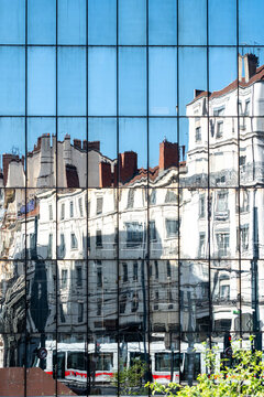 Historic buildings reflected in a blue glass facade create a distorted urban cityscape where the facade turns reflected architecture into blue glass