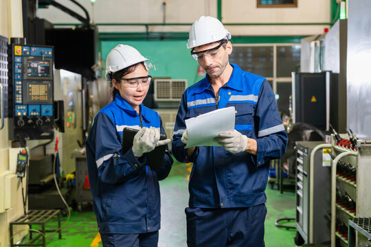 Diverse team of industrial engineers working together and inspecting documentation in factory plant, industrial workers team with tablet and document reviewing project data in automotive parts