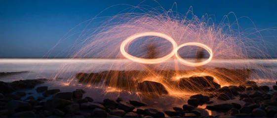 Steel wool light painting circles on rocky beach at dusk © SR07XC3