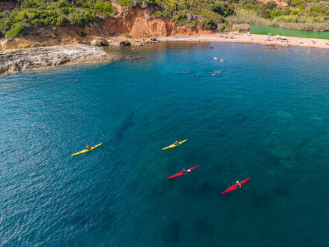 Aerial view of people kayaking in the clear blue waters of the Tyrrhenian Sea near the Laghetto di Terra Nera beach in Porto Azzurro, Tuscany, Elba island, Italy.