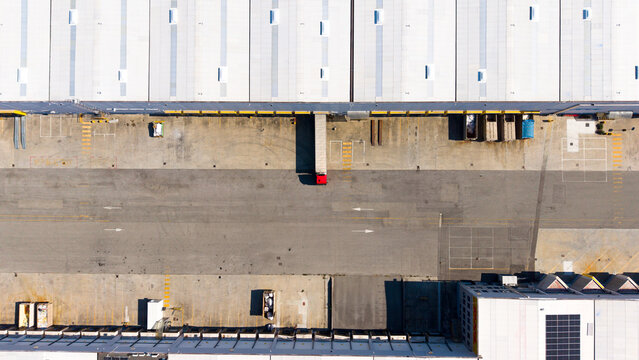 Aerial view of a semi truck parked at a loading dock of a large distribution center, showing warehouse logistics and freight handling in Liscate, Lombardy, Italy.