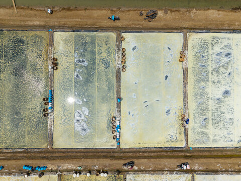Aerial view of Salt Ponds with workers collecting salt in rectangular pools in Kedung, Central Java, Indonesia.