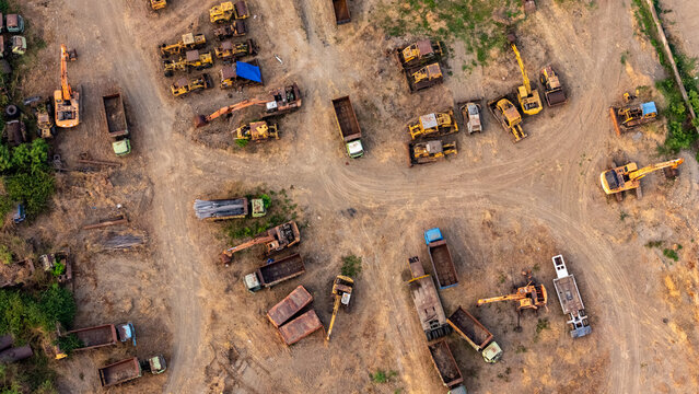 Aerial view of a construction equipment yard filled with various excavators, dump trucks, and heavy machinery parked on a dusty ground in Semarang, Central Java, Indonesia.