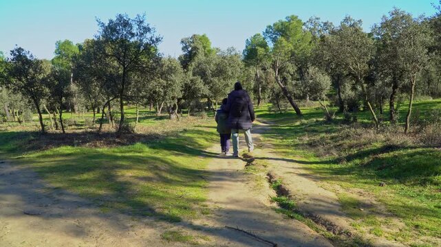 back shot of mother and boy walking a path on a sunny winter day