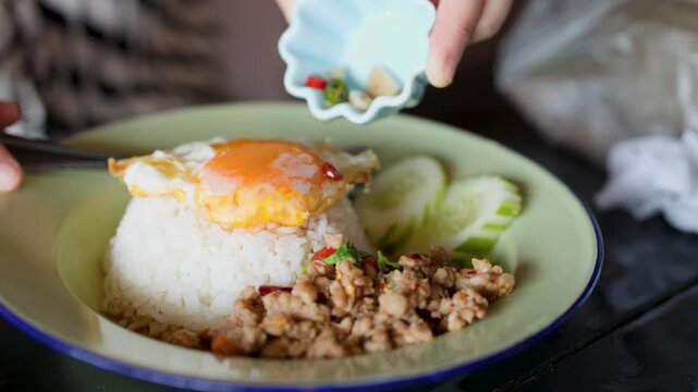 Pouring Chili Fish Sauce Over Pad Krapow and Fried Egg