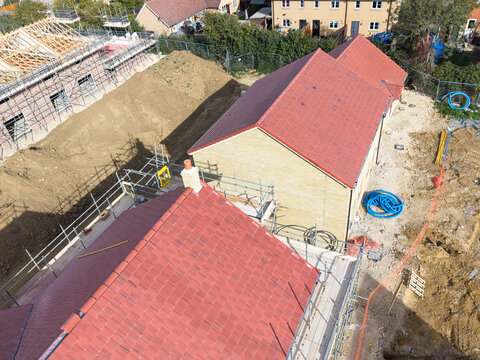 Interesting drone view of a new completed tiled roof on a new house in a British housing development site in East Anglia. The site will be available to first time buyers.