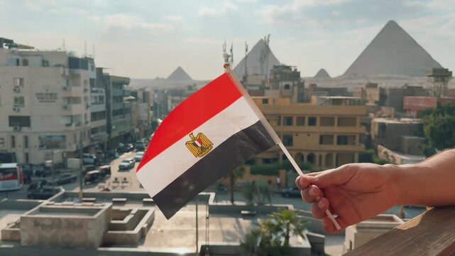 Hand waving the Egyptian flag overlooking street traffic and the Great Pyramids of Giza video clip