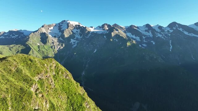 Drone flight above Caucasus mountains landscape at sunset seen from Mkheri church mountain. Famous peaks of Georgia: Ushba, Laila and Shkhara.