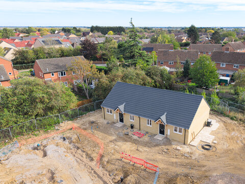 Interesting drone UAV view of near completed semi detached retirement bungalows seen on a housing development site in England. An older 1960s estate is just beyond the tree line.
