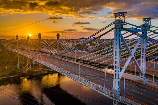 Aerial view of the Juan Pablo Duarte and Professor Juan Bosch bridges at sunset, with golden light reflecting on the river in Santo Domingo Este, Santo Domingo Provinc, Dominican Republic.