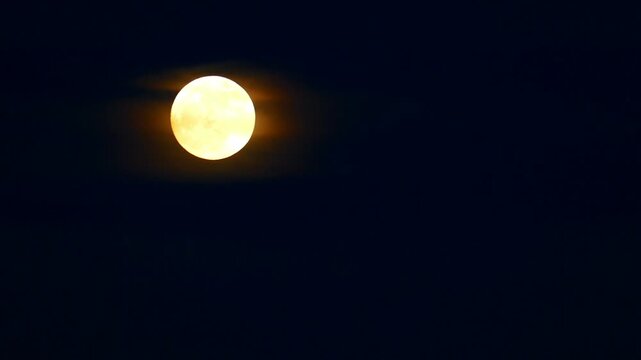Spooky full moon rising in the dark night sky timelapse. Cinematic celestial background video asset for creative projects about Halloween horror films vampire lore and werewolf stories.