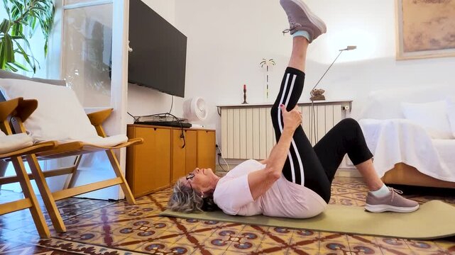 Senior woman stretching leg muscles at home