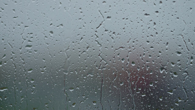 Rain drop hitting window glass and sliding down